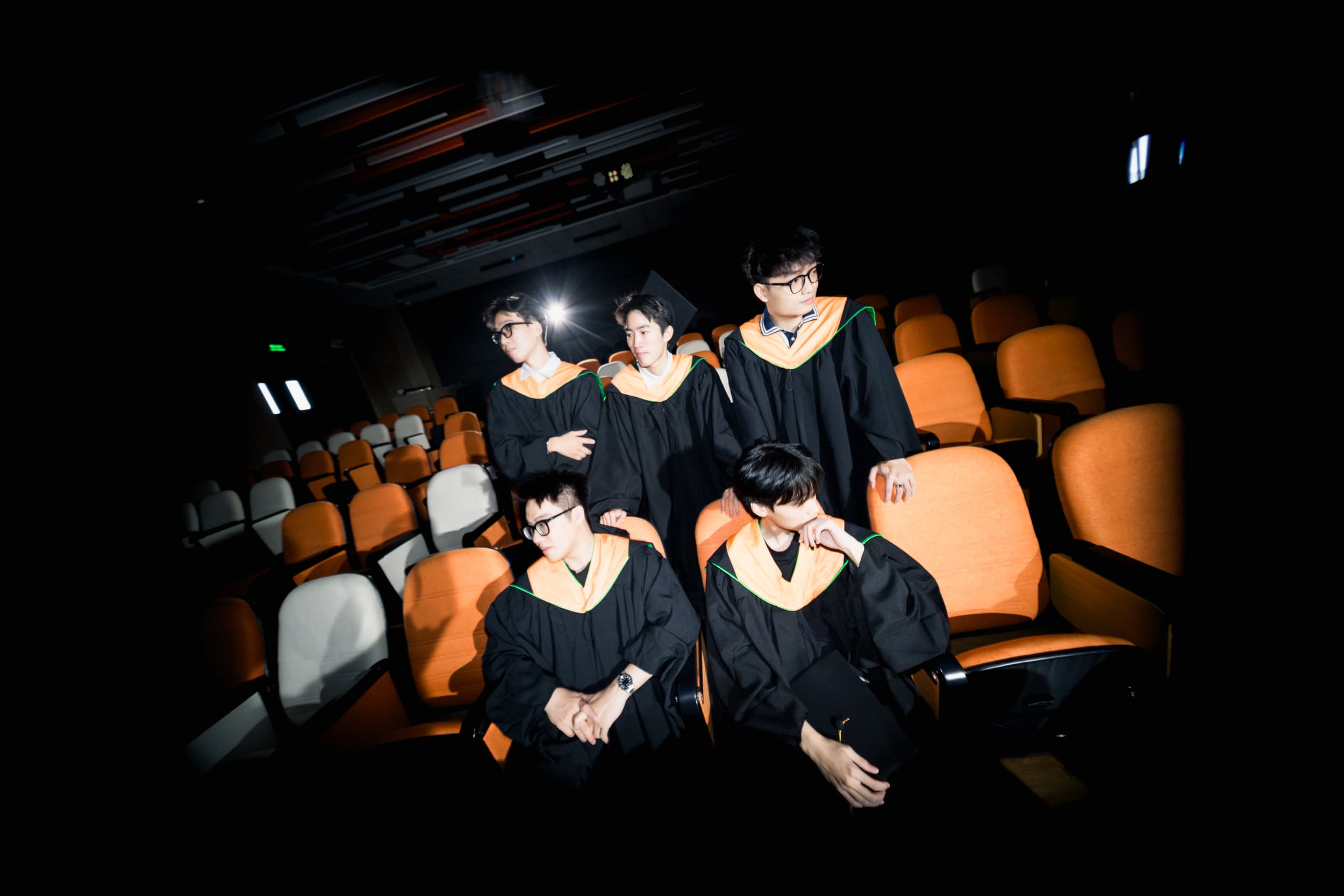 Wide-angle group portrait of five graduates in the auditorium
